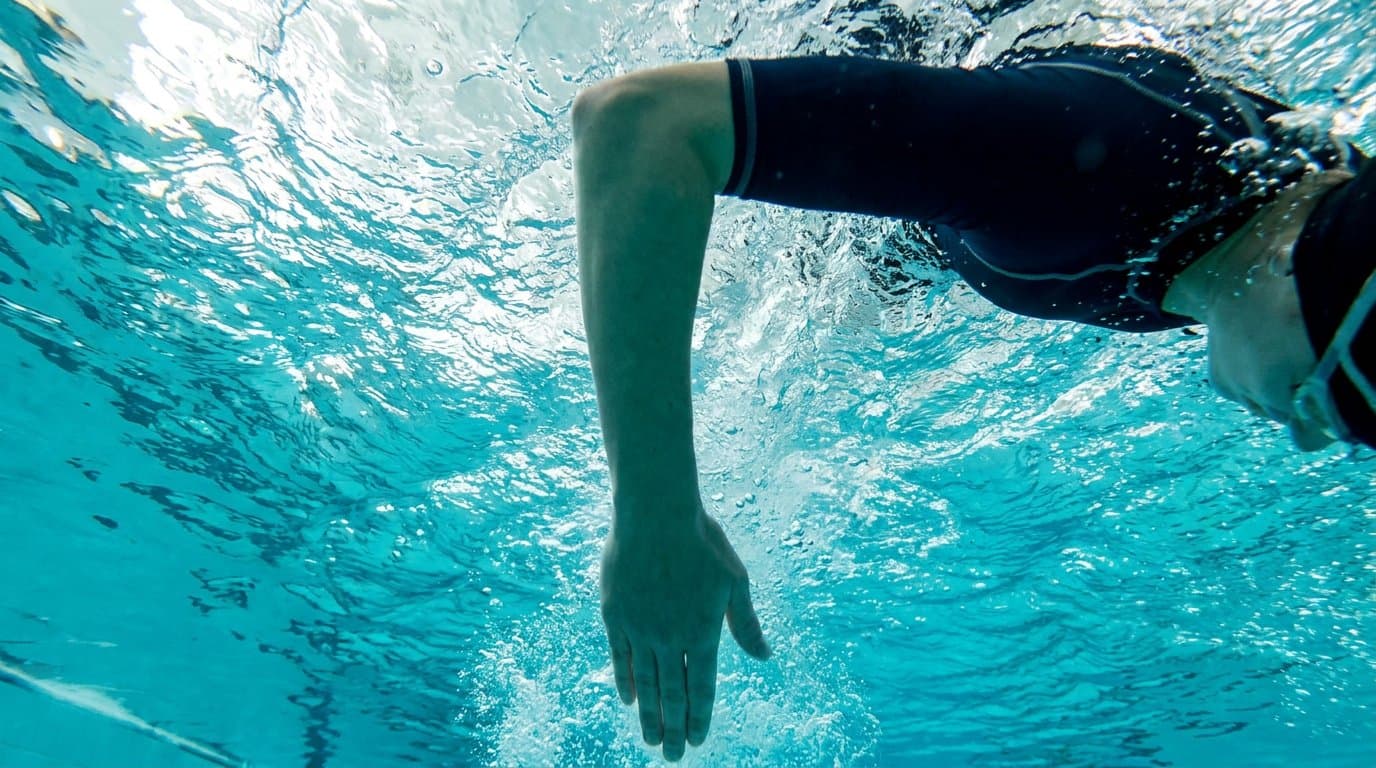 Unterarm eines Kraulschwimmers in der Catch-Phase mit hohem Ellbogen – Unterwasseraufnahme.